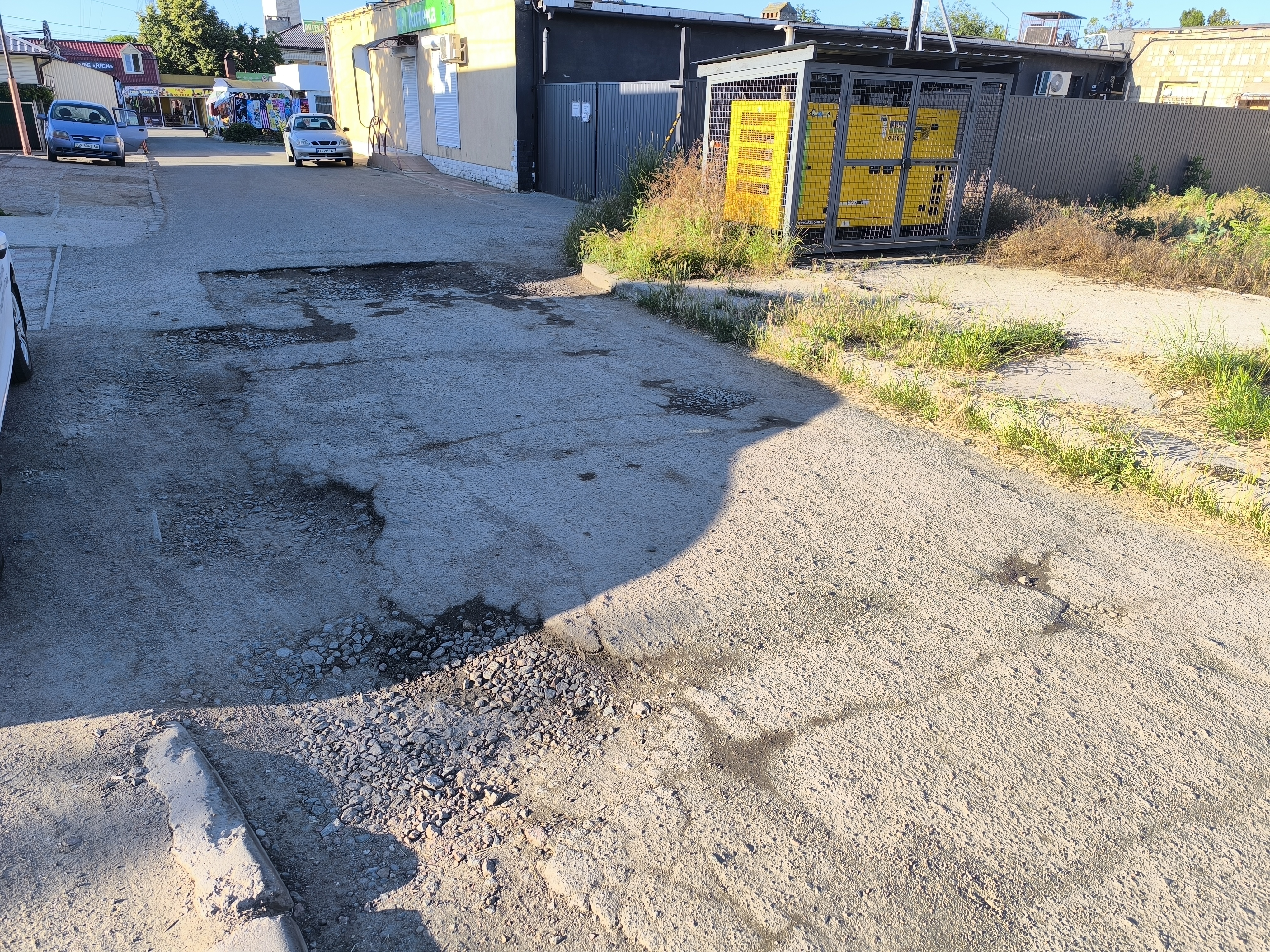 Розбите асфальтове покриття з вибоїнами і щебенем на дорозі в Кароліно-Бугазі